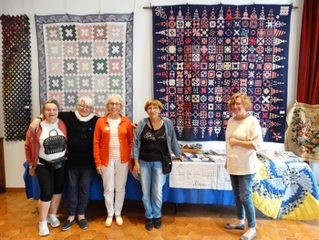 Des membres de l'association de fil en aiguille devant quelques oeuvres de leur exposition de patchwork