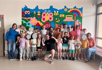 Les animateurs, les enfants et l'artiste devant la fresque terminée.