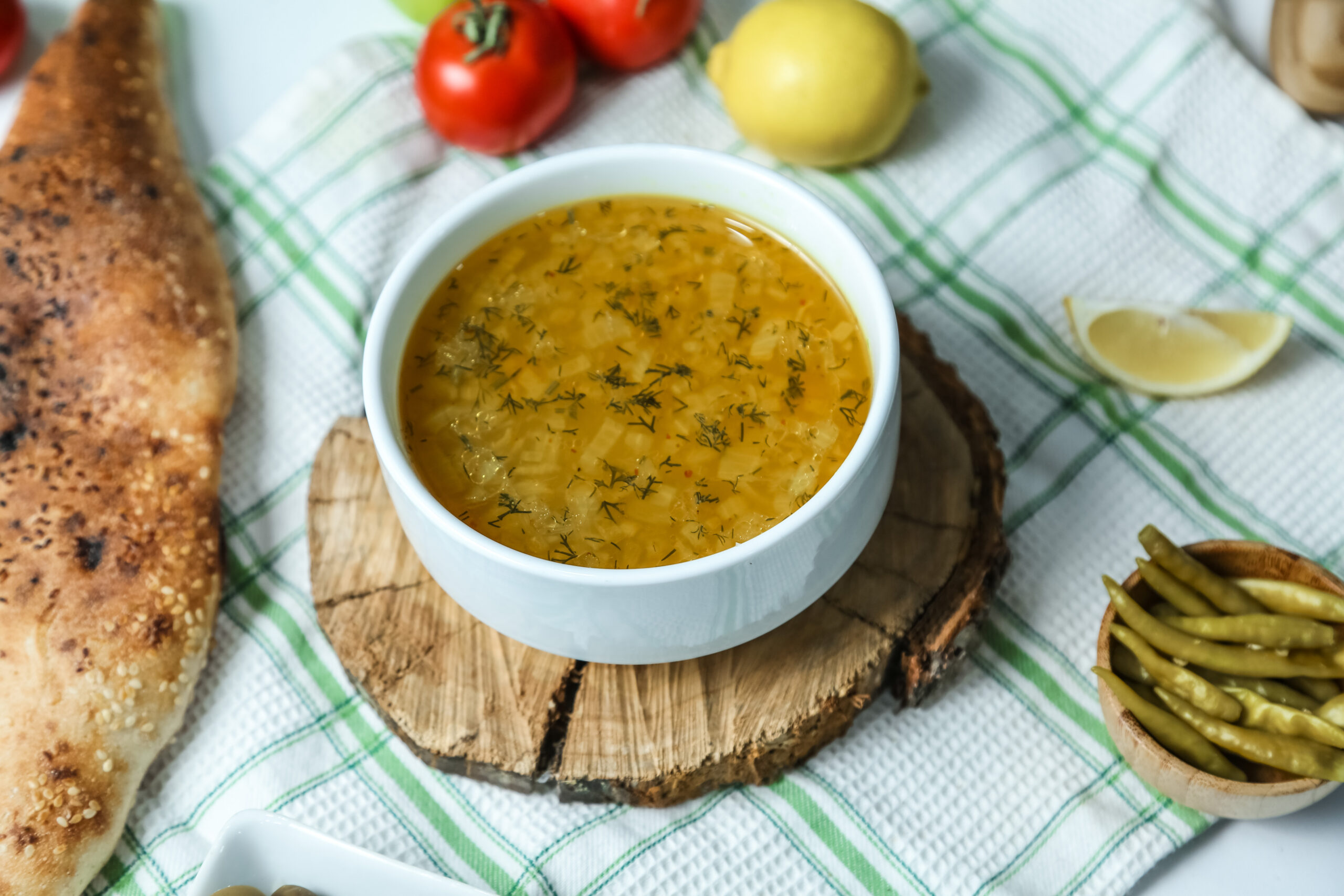 rice soup in the bowl on the wooden board greens pepper lemon tomato side view